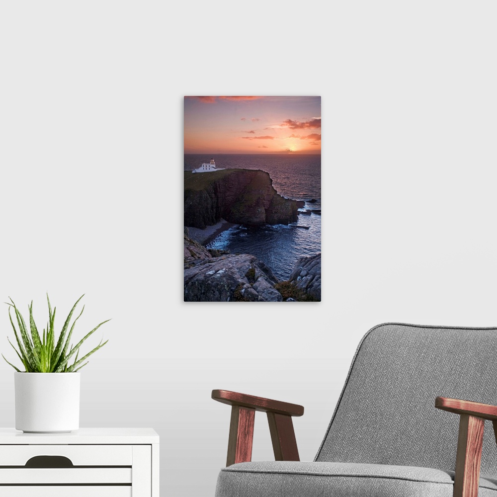 A modern room featuring A sunset seascape over Neist Point Lighthouse, Isle of Skye, Scotland with a peach and gold sky.