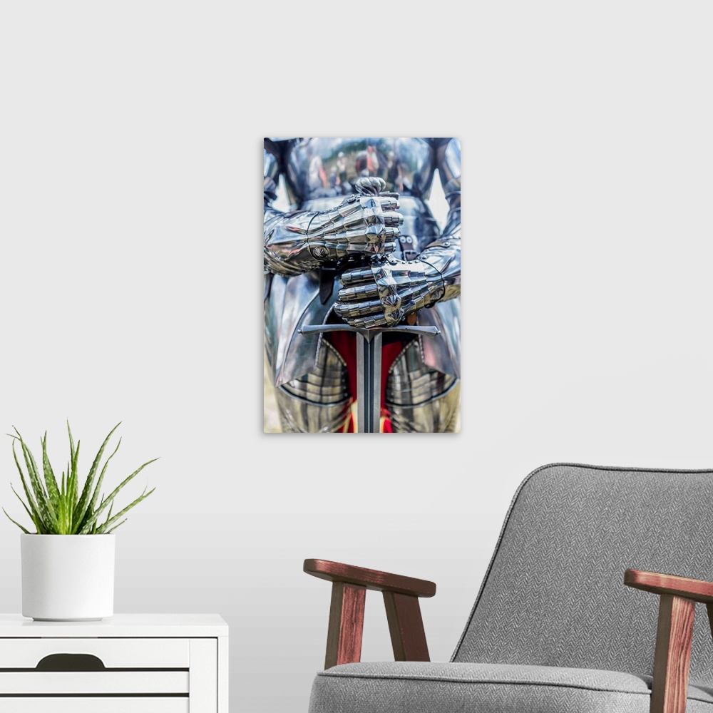 A modern room featuring A photograph of a close-up on a suit of armor holding a sword.