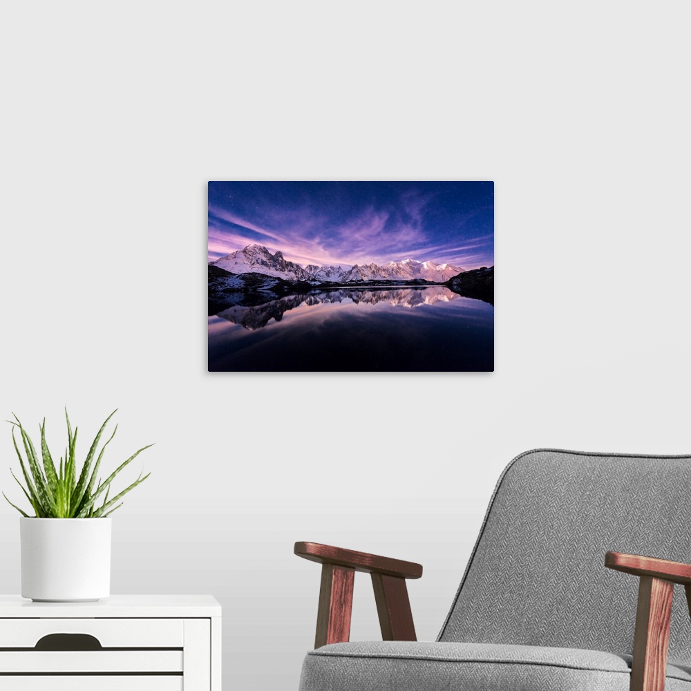 A modern room featuring Fine art photograph of a snowy mountain range reflected in the water under a lavender sky in France.