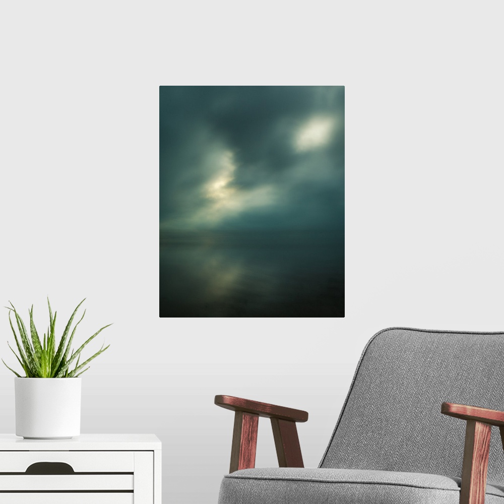 A modern room featuring Dream-like photograph of a calm ocean with the sun starting to peak through a cloudy sky.