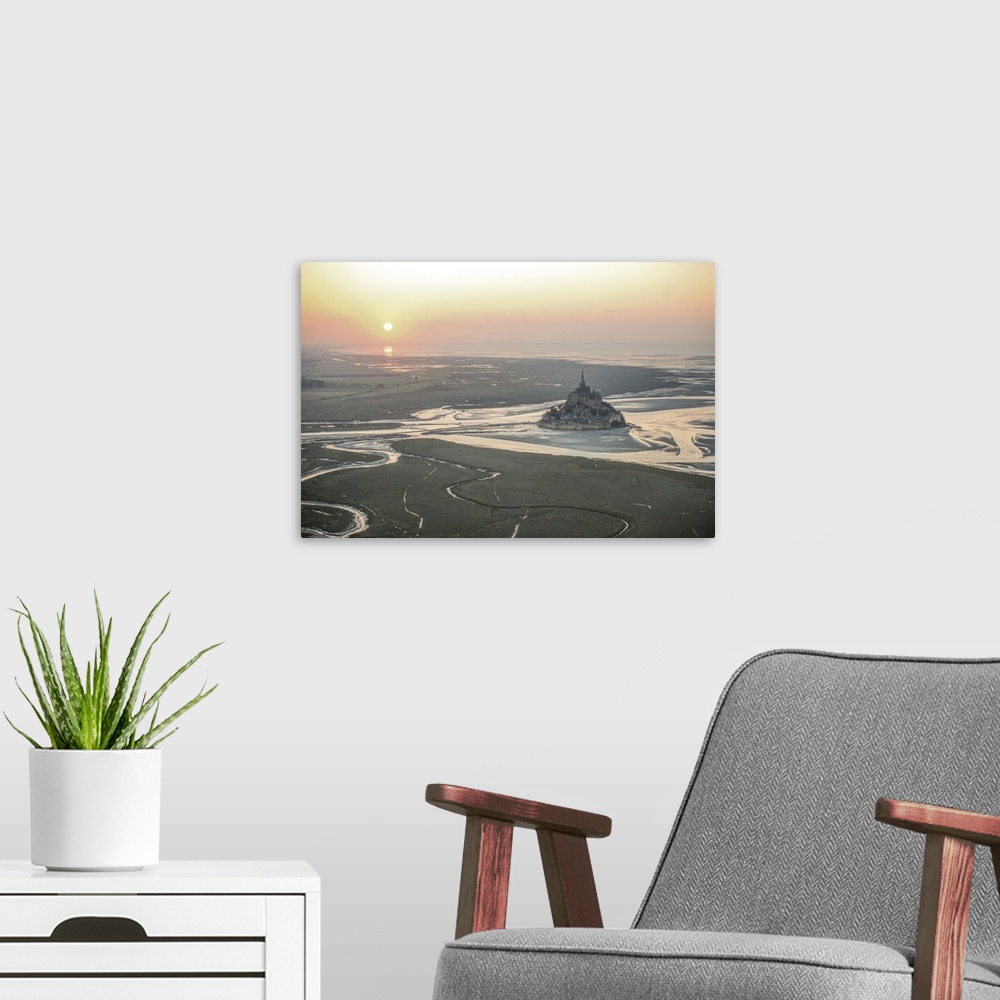 A modern room featuring Mont Saint Michel in France at low tide under the setting sun.