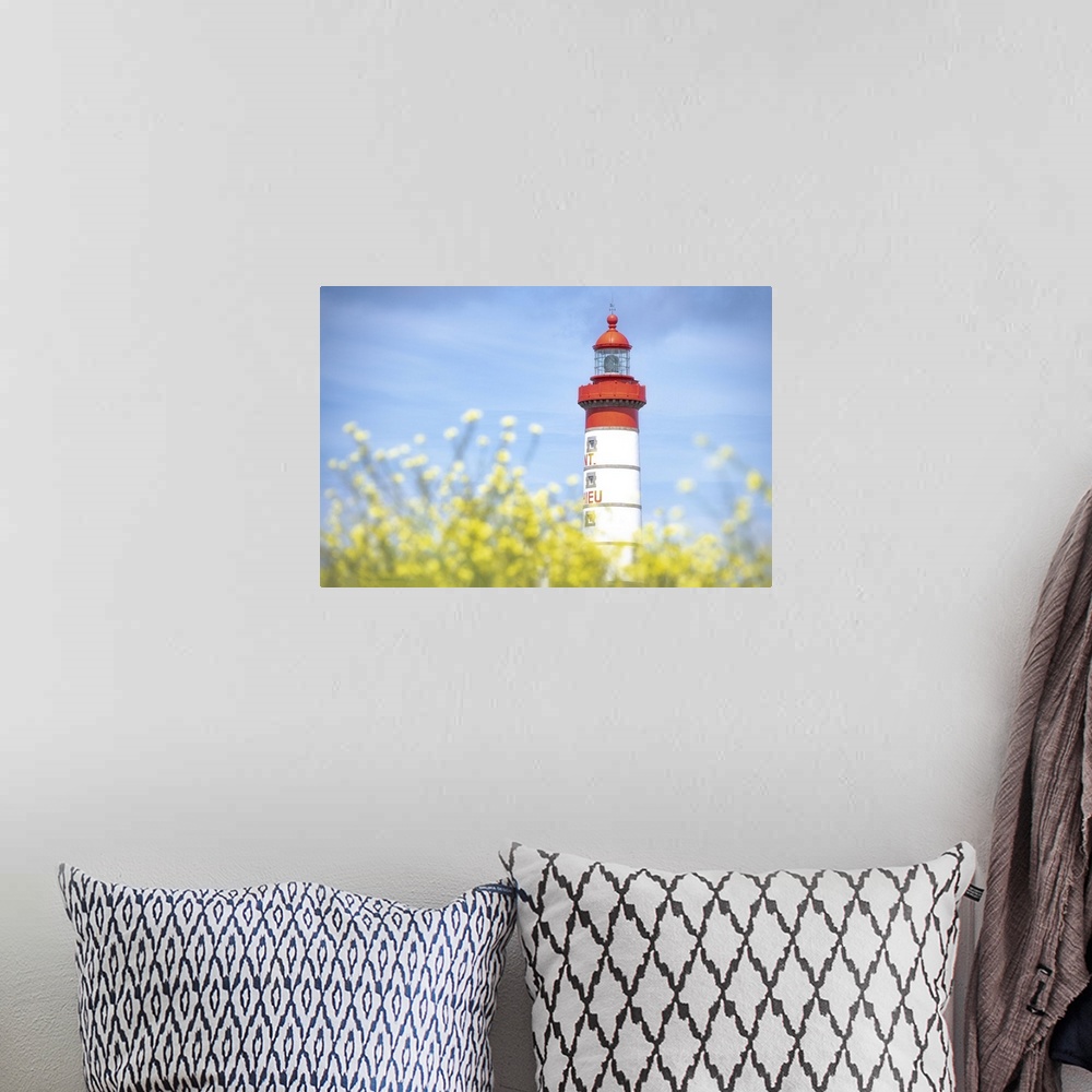 A bohemian room featuring Saint Mathieu lighthouse under a blue sky and behind yellow flowers in Plougonvelin, France.