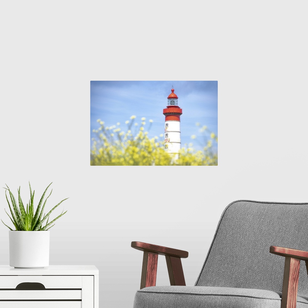 A modern room featuring Saint Mathieu lighthouse under a blue sky and behind yellow flowers in Plougonvelin, France.