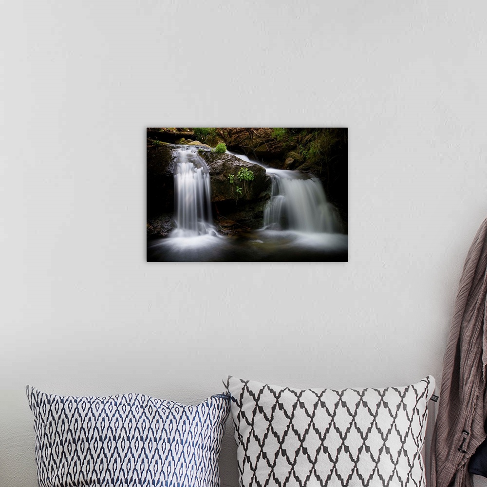 A bohemian room featuring A photograph of a waterfall streaming down rocks in a forest.