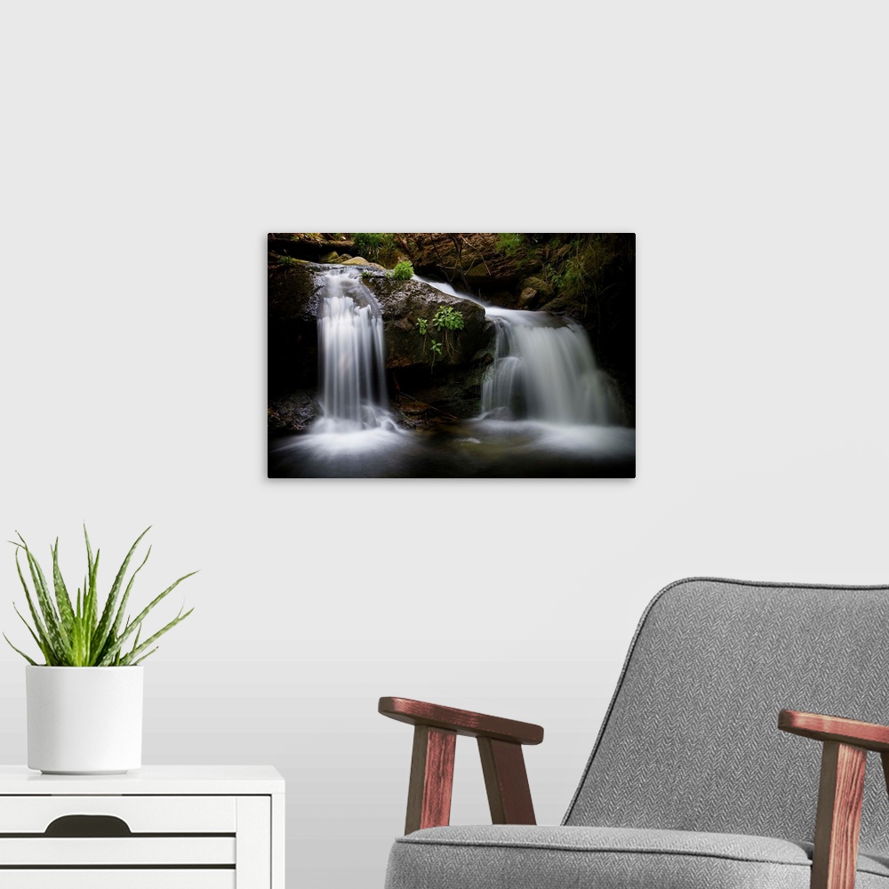 A modern room featuring A photograph of a waterfall streaming down rocks in a forest.