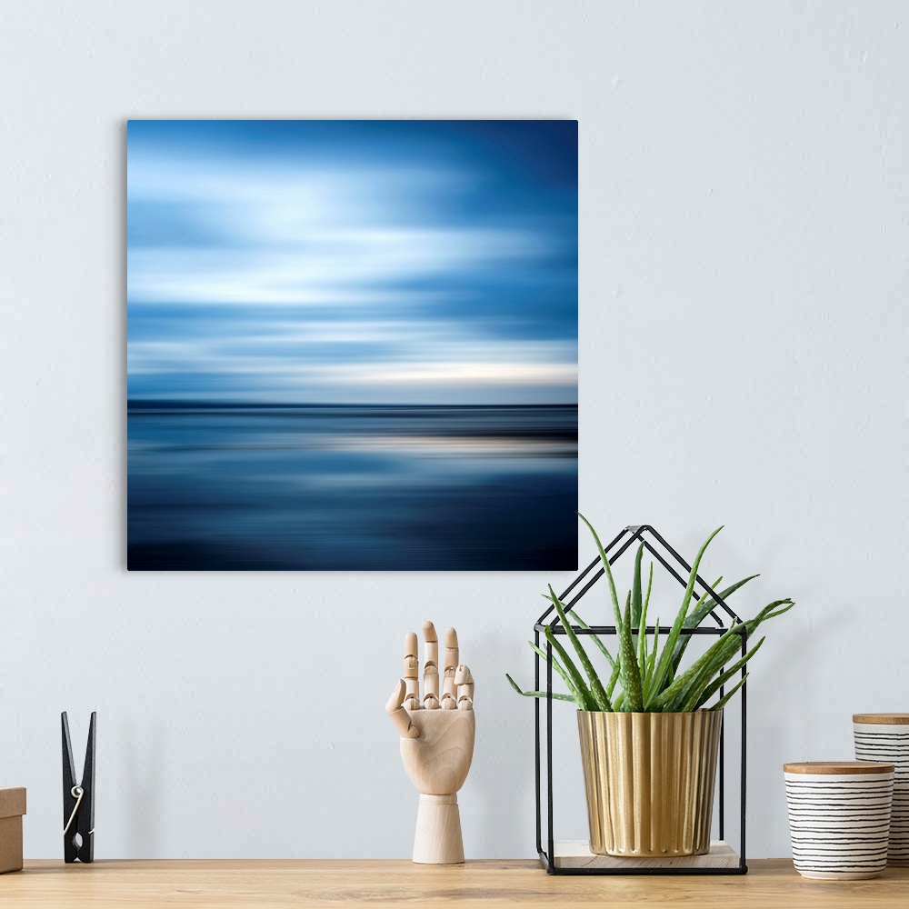 A bohemian room featuring Huge square abstract art of an ocean against a clear sky that includes a lot of horizontal lines.