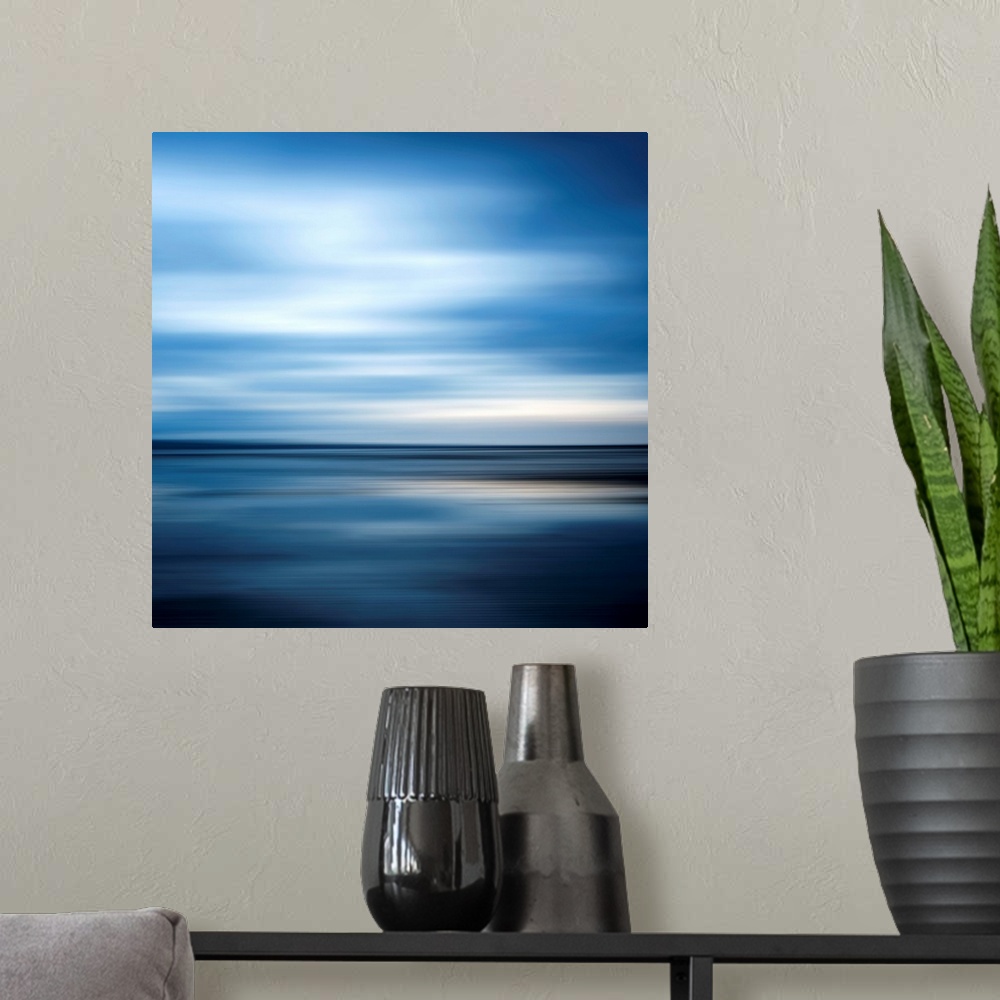A modern room featuring Huge square abstract art of an ocean against a clear sky that includes a lot of horizontal lines.