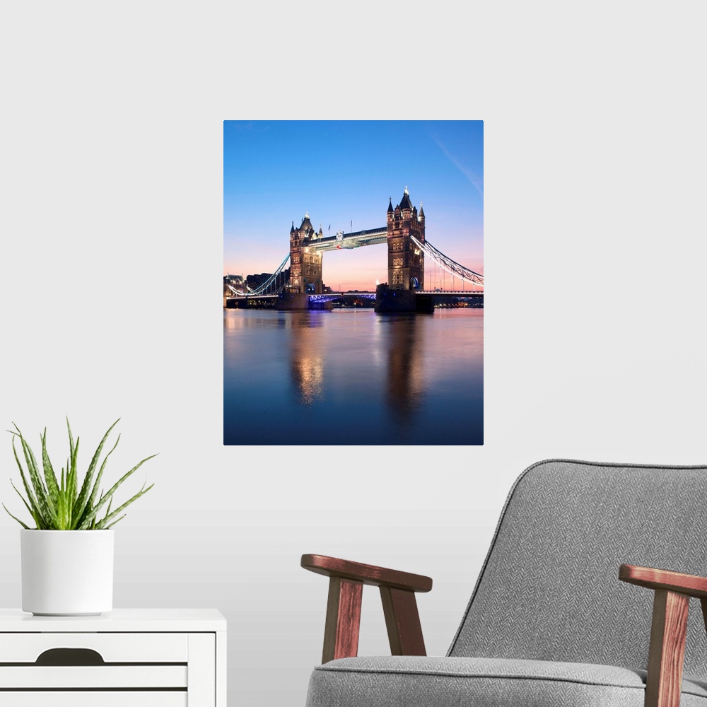 A modern room featuring Tower Bridge, London, UK at sunrise with a clear blue sky and reflections in the River Thames.