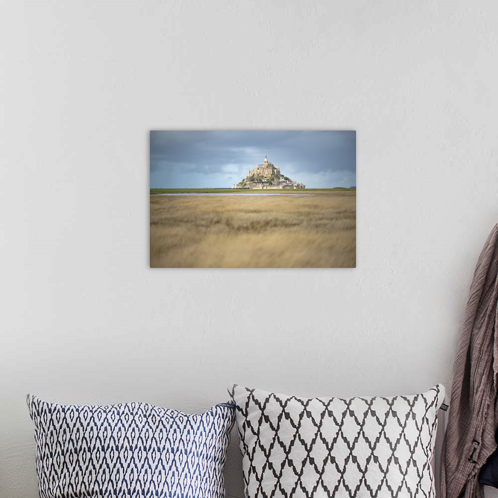 A bohemian room featuring Mont Saint Michel in France in the middle of the meandres under a blue sky.