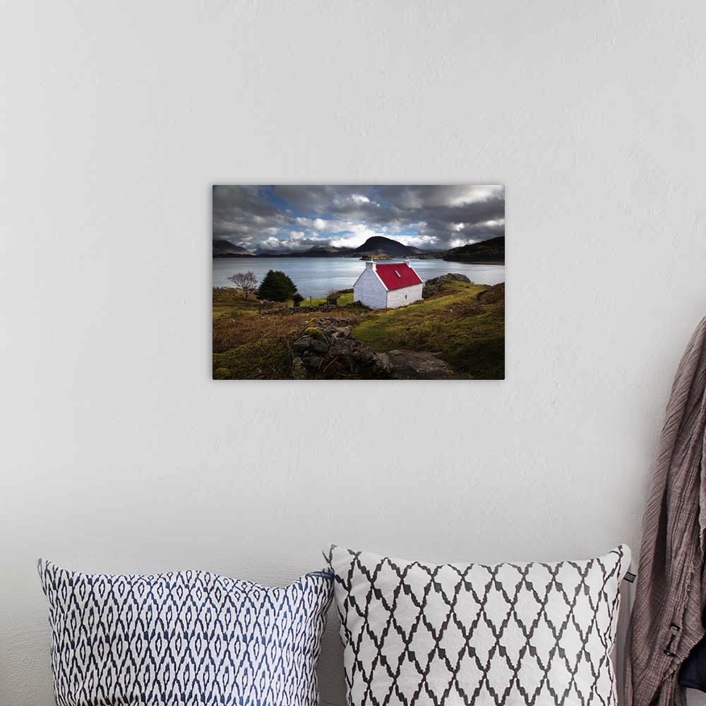 A bohemian room featuring Red roofed cottage in romantic Scottish Highlands wiht blue lake and fluffy clouds in the light b...