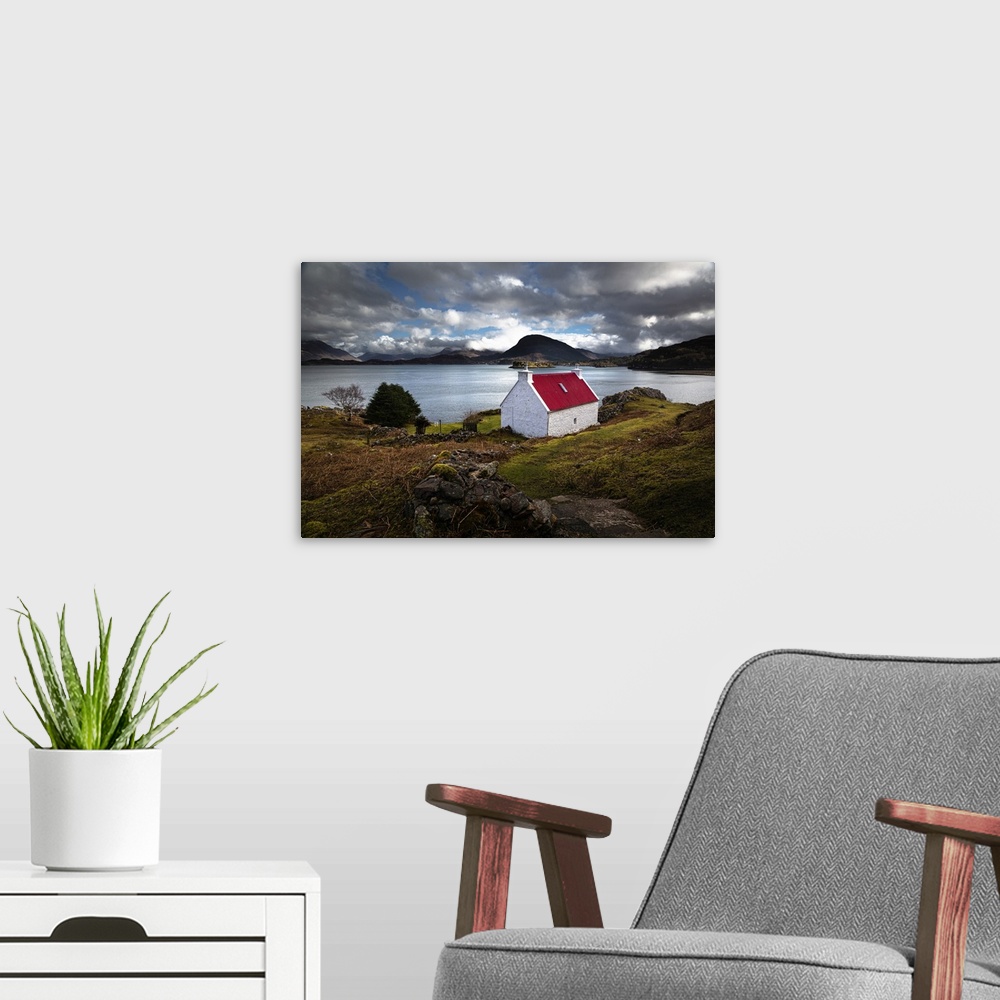 A modern room featuring Red roofed cottage in romantic Scottish Highlands wiht blue lake and fluffy clouds in the light b...