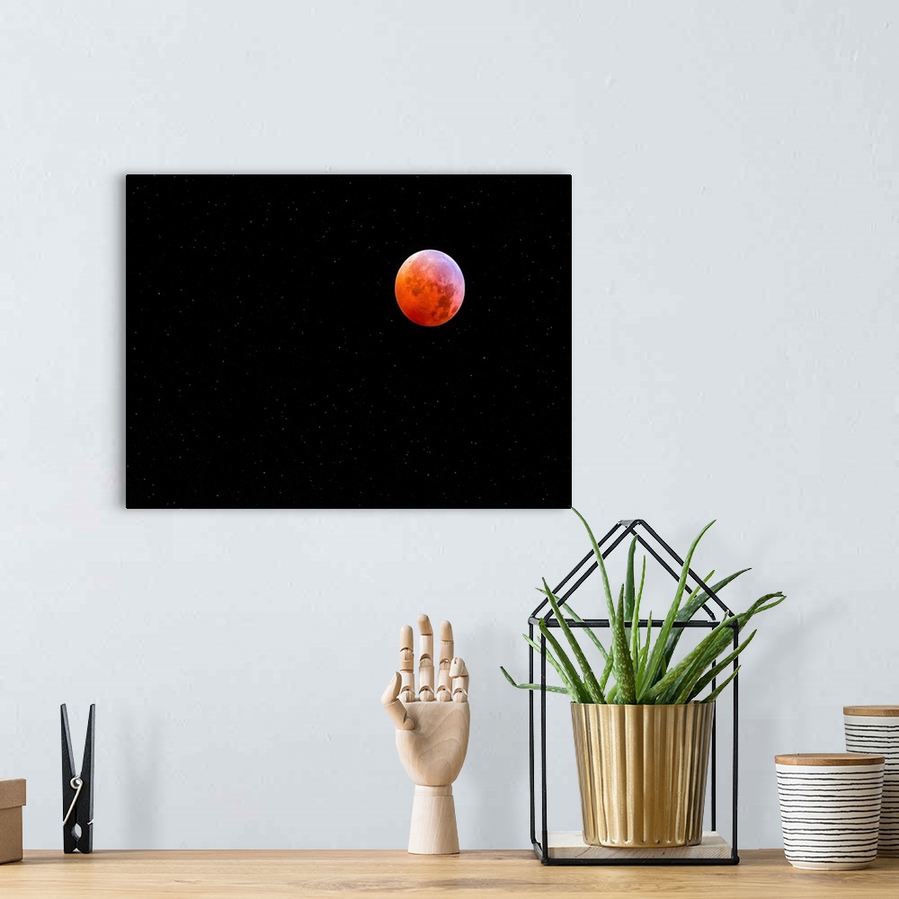 A bohemian room featuring The moon in a starry night sky glowing bright red during an eclipse.