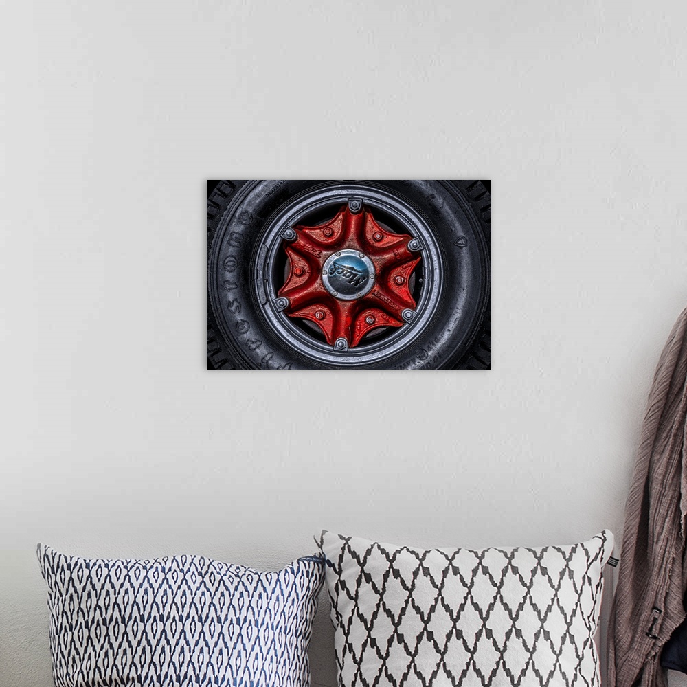 A bohemian room featuring Large tire and red hubcap of a Mack truck.