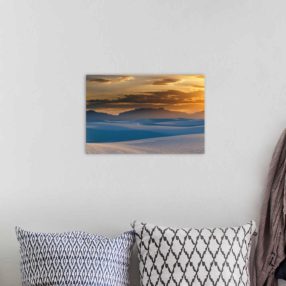 A bohemian room featuring Large landscape photograph of the sun setting in a cloudy sky, over the Gypsum dunes, White Sands...