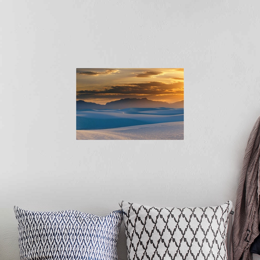 A bohemian room featuring Large landscape photograph of the sun setting in a cloudy sky, over the Gypsum dunes, White Sands...