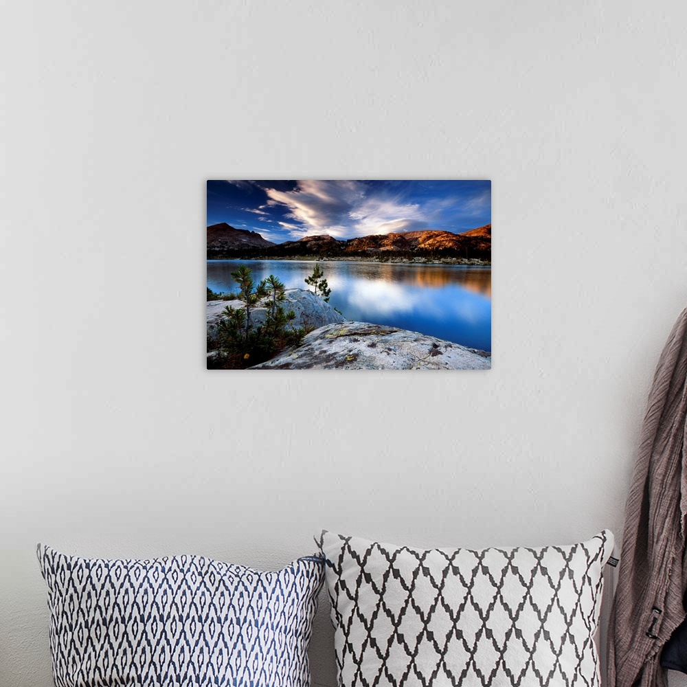 A bohemian room featuring Sunset lit clouds hover over a mountain range that is photographed from across a body of water wi...