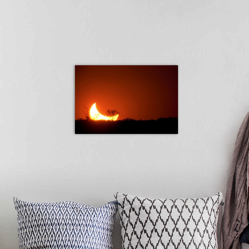 A bohemian room featuring Sun and moon set in a partial eclipse on horizon