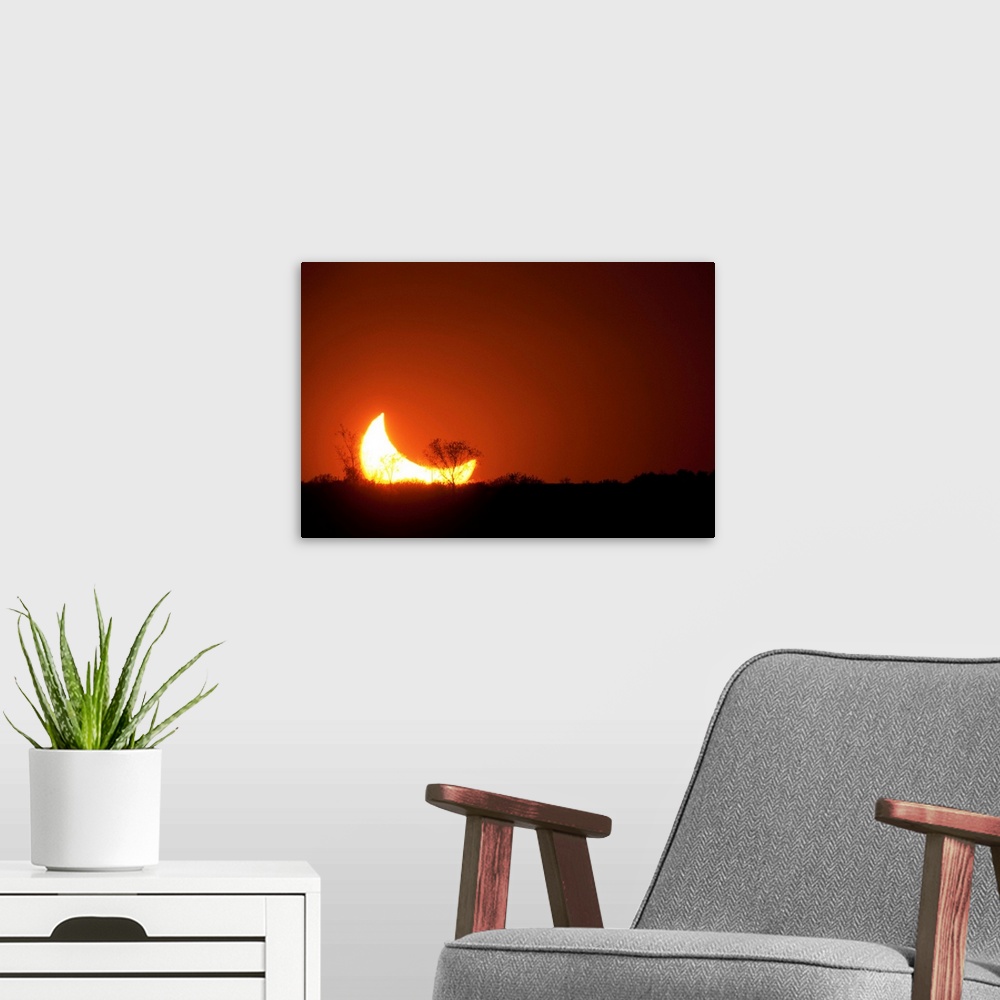A modern room featuring Sun and moon set in a partial eclipse on horizon