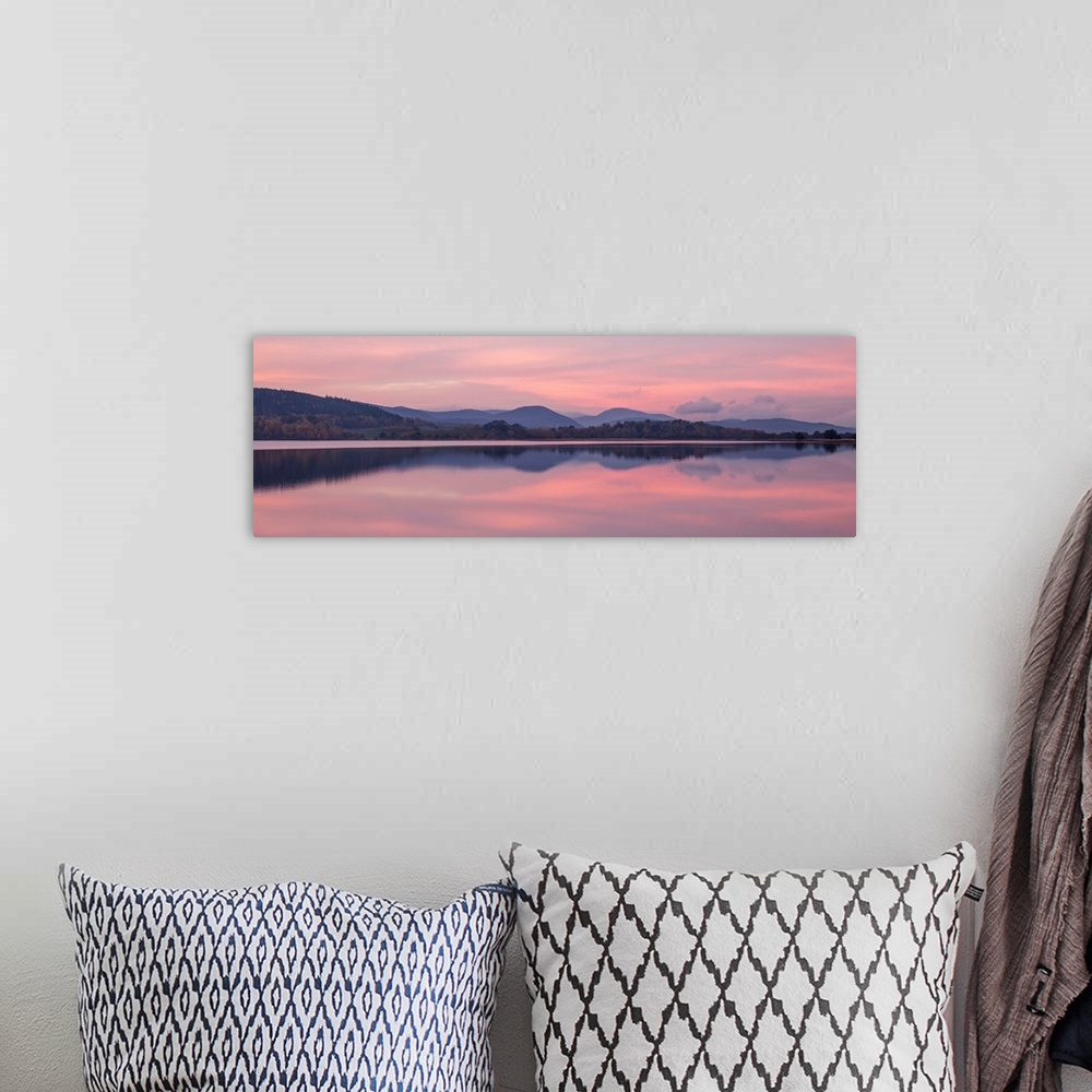 A bohemian room featuring A photograph of a sunrise sky over a countryside landscape.