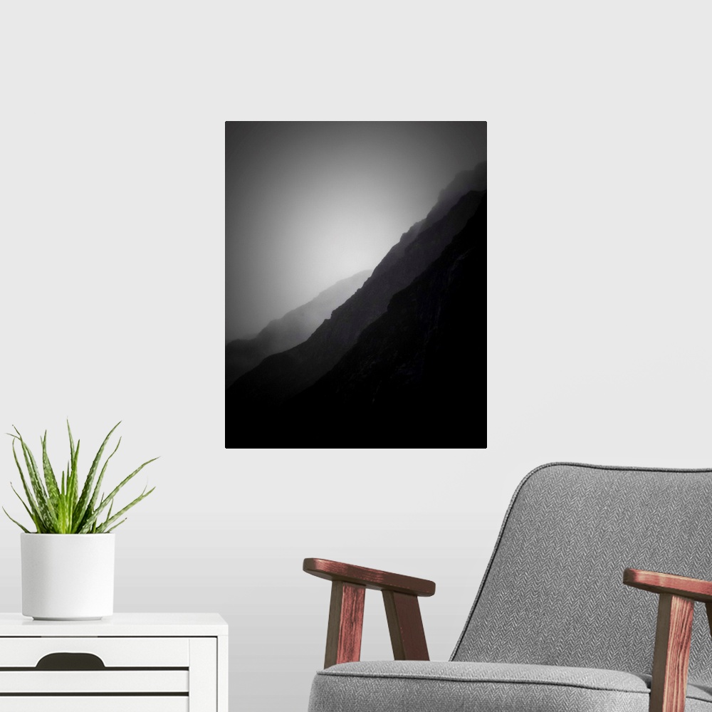 A modern room featuring A black and white photograph of silhouetted mountain sides shrouded in haze.