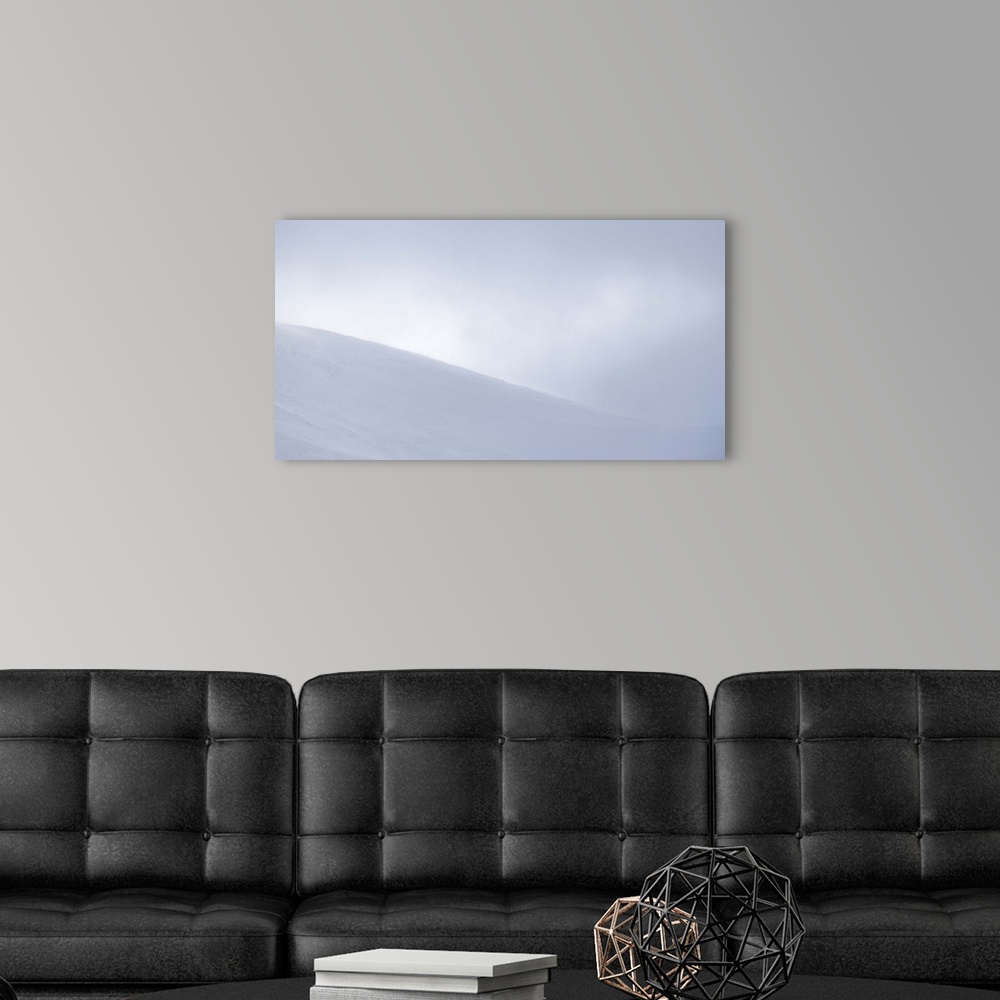 A modern room featuring An obscured view of a mountain top covered in snow and surrounded by fog.