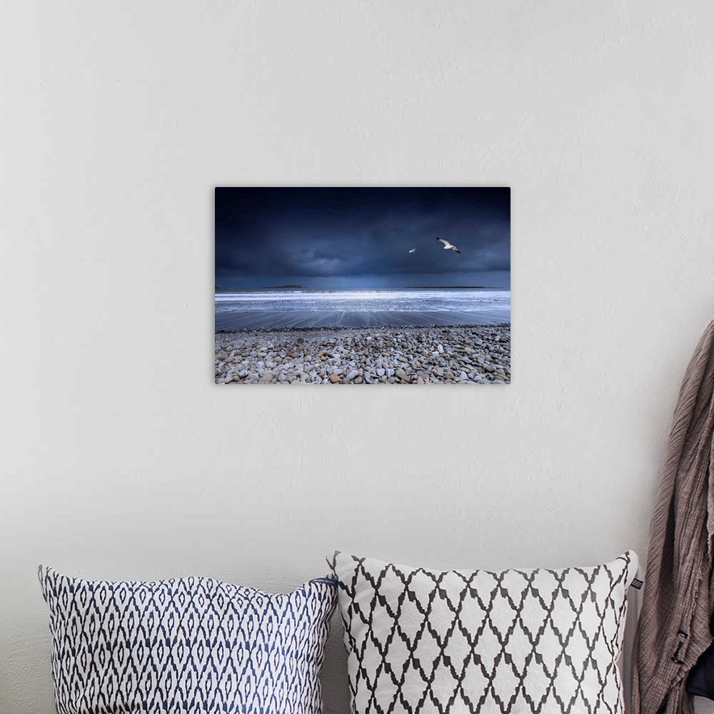 A bohemian room featuring Fine art photo of a rocky beach on the ocean shore with two seagulls in the dark, stormy sky.