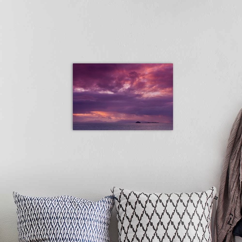 A bohemian room featuring Fine art photo of a dramatic skyscape over a calm ocean with a small island in the distance.