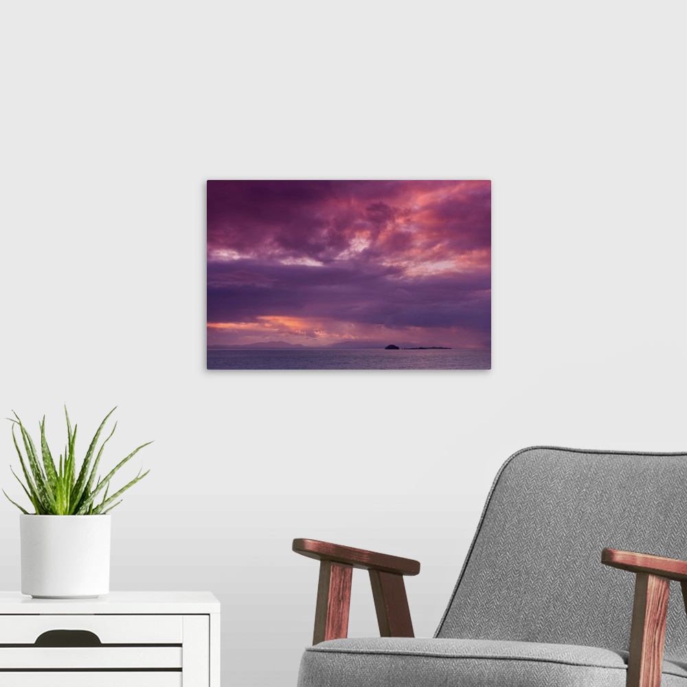 A modern room featuring Fine art photo of a dramatic skyscape over a calm ocean with a small island in the distance.