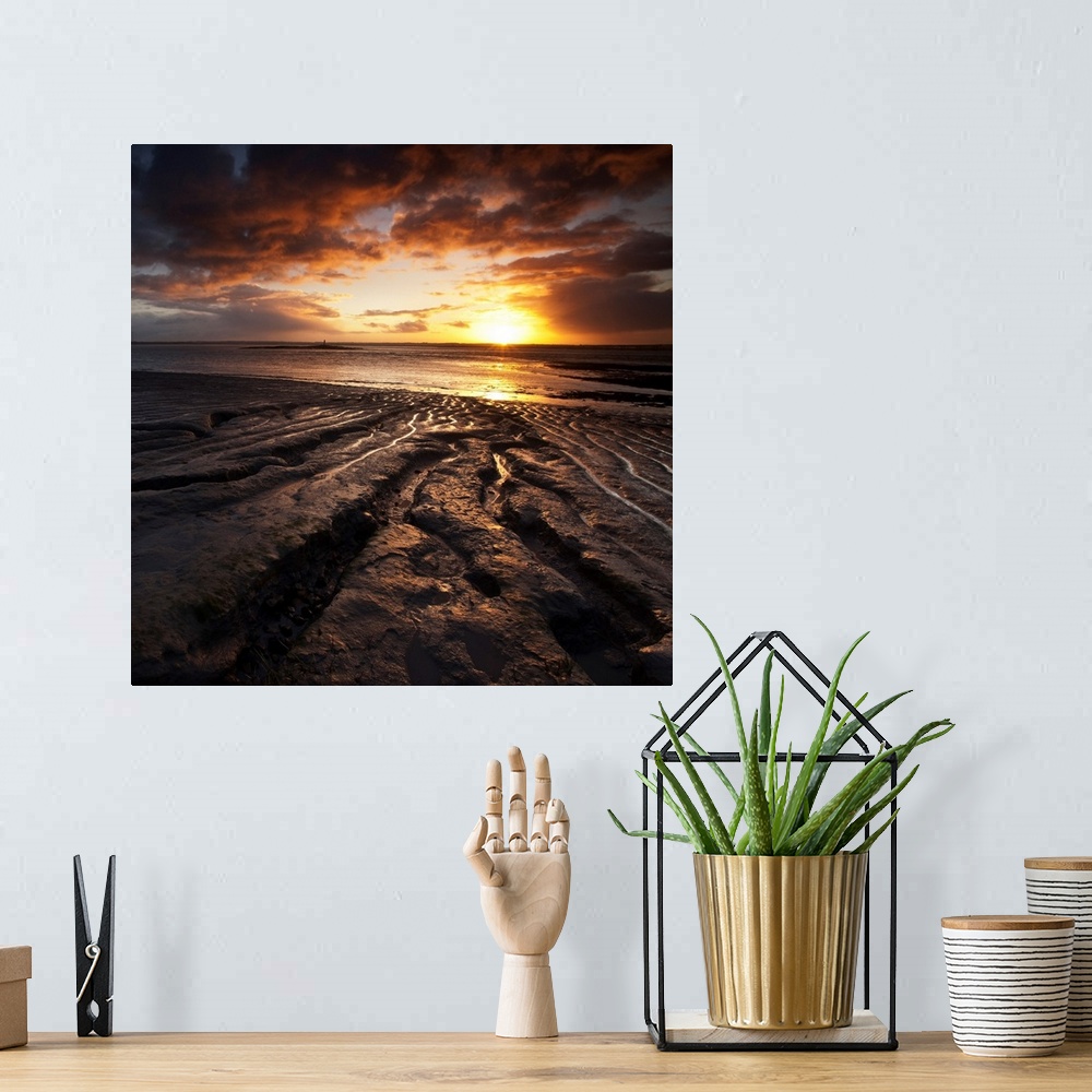 A bohemian room featuring Square warm orange and yellow glowing sunrise over rocks and sea with beautiful clouds.