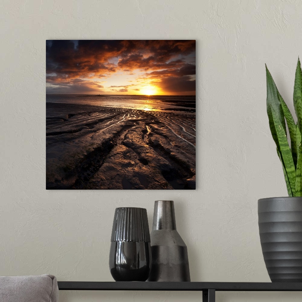 A modern room featuring Square warm orange and yellow glowing sunrise over rocks and sea with beautiful clouds.