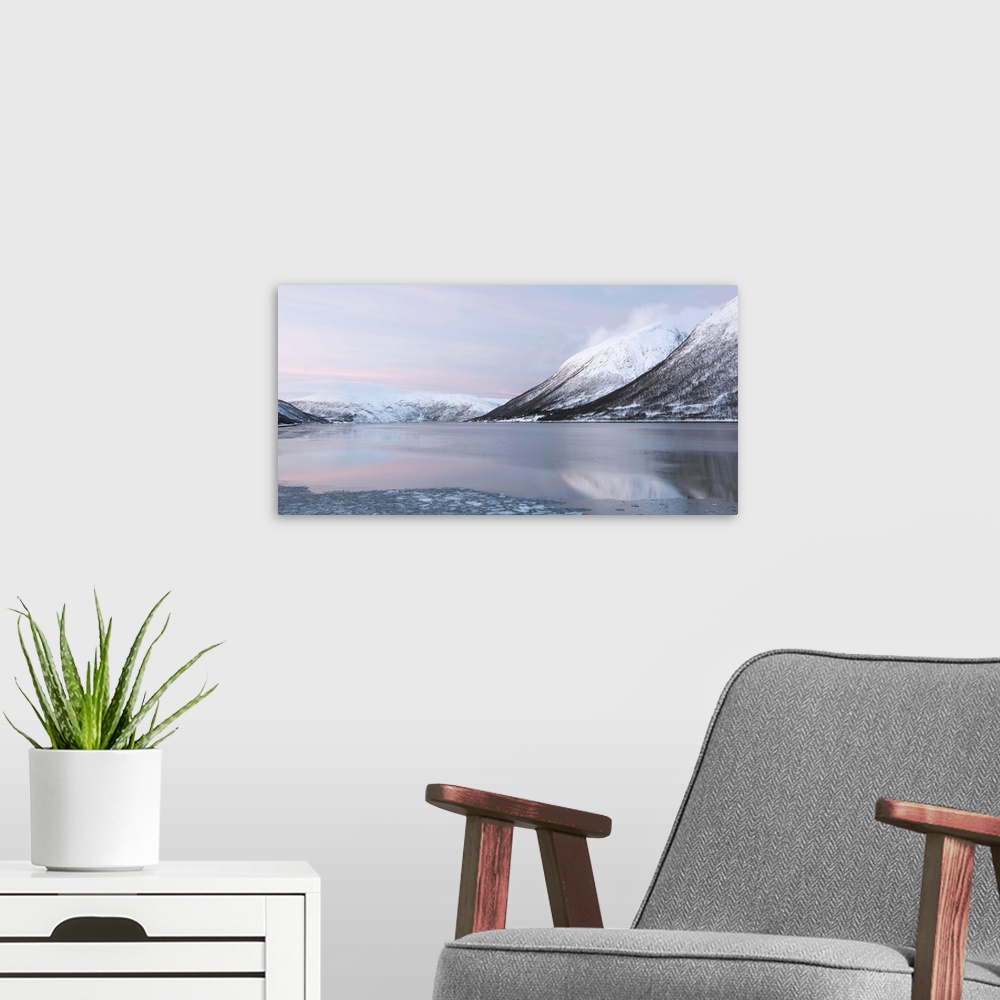 A modern room featuring A tranquil cool pink blue mountainscape dawn in the Norweigian snow by a lake.