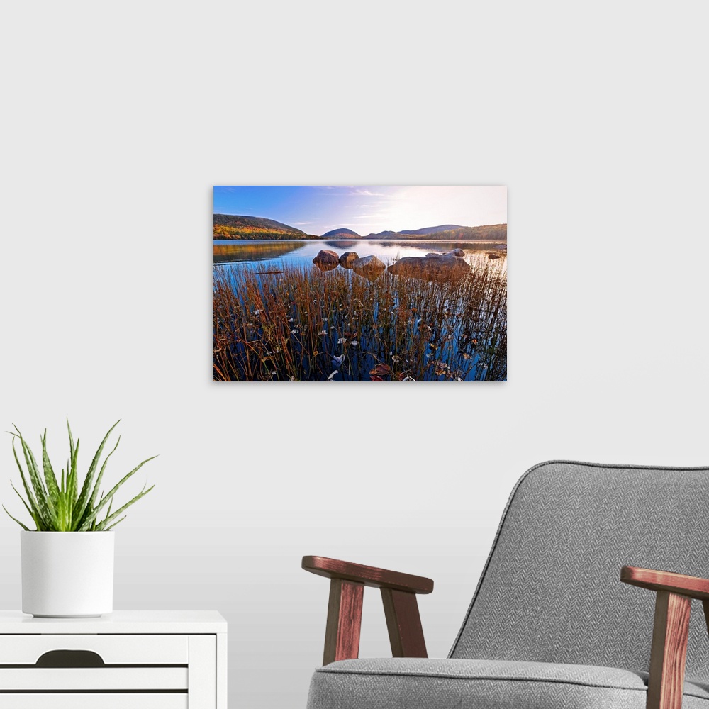 A modern room featuring This large piece is a photograph taken over a large body of water with a scenic view of hills in ...