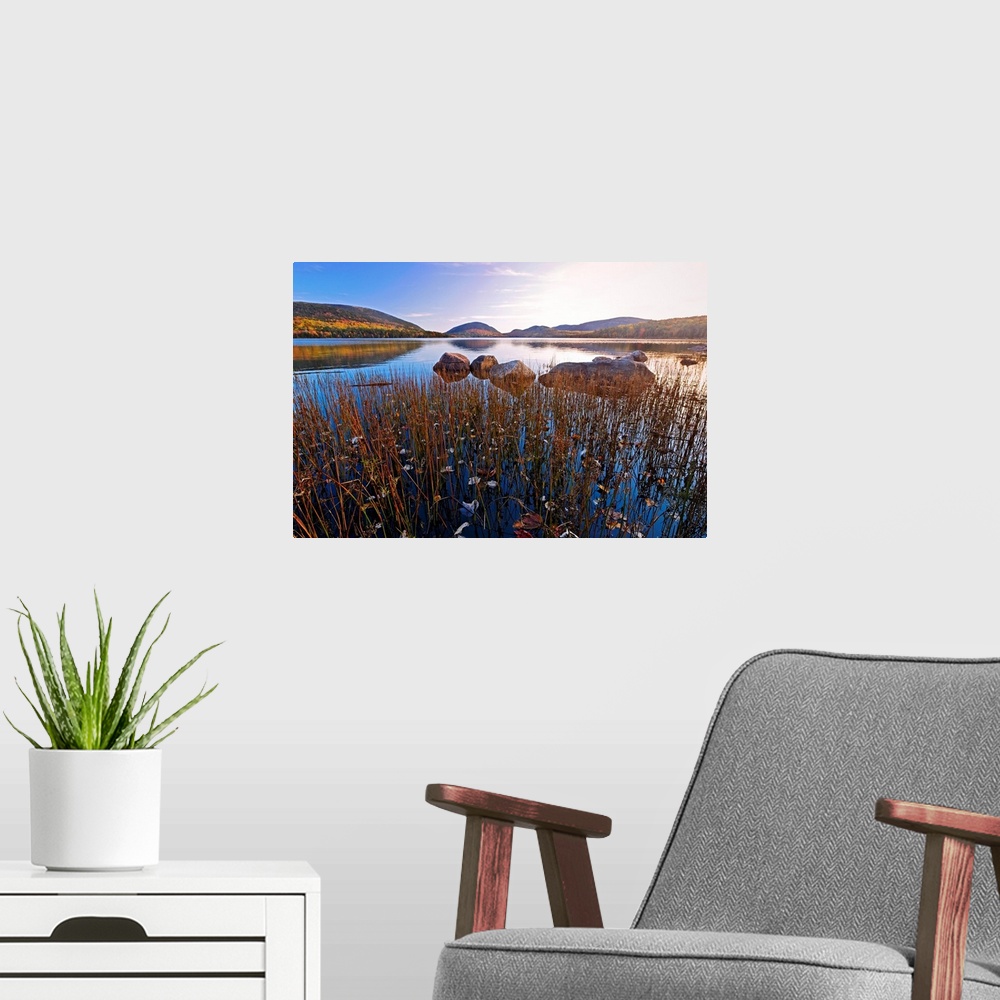 A modern room featuring This large piece is a photograph taken over a large body of water with a scenic view of hills in ...
