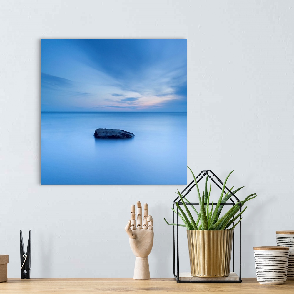 A bohemian room featuring A zen calm minimal minimalist cool deep blue image of one rock in a flat calm sea.