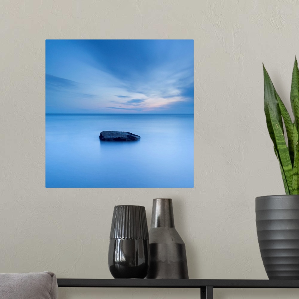 A modern room featuring A zen calm minimal minimalist cool deep blue image of one rock in a flat calm sea.
