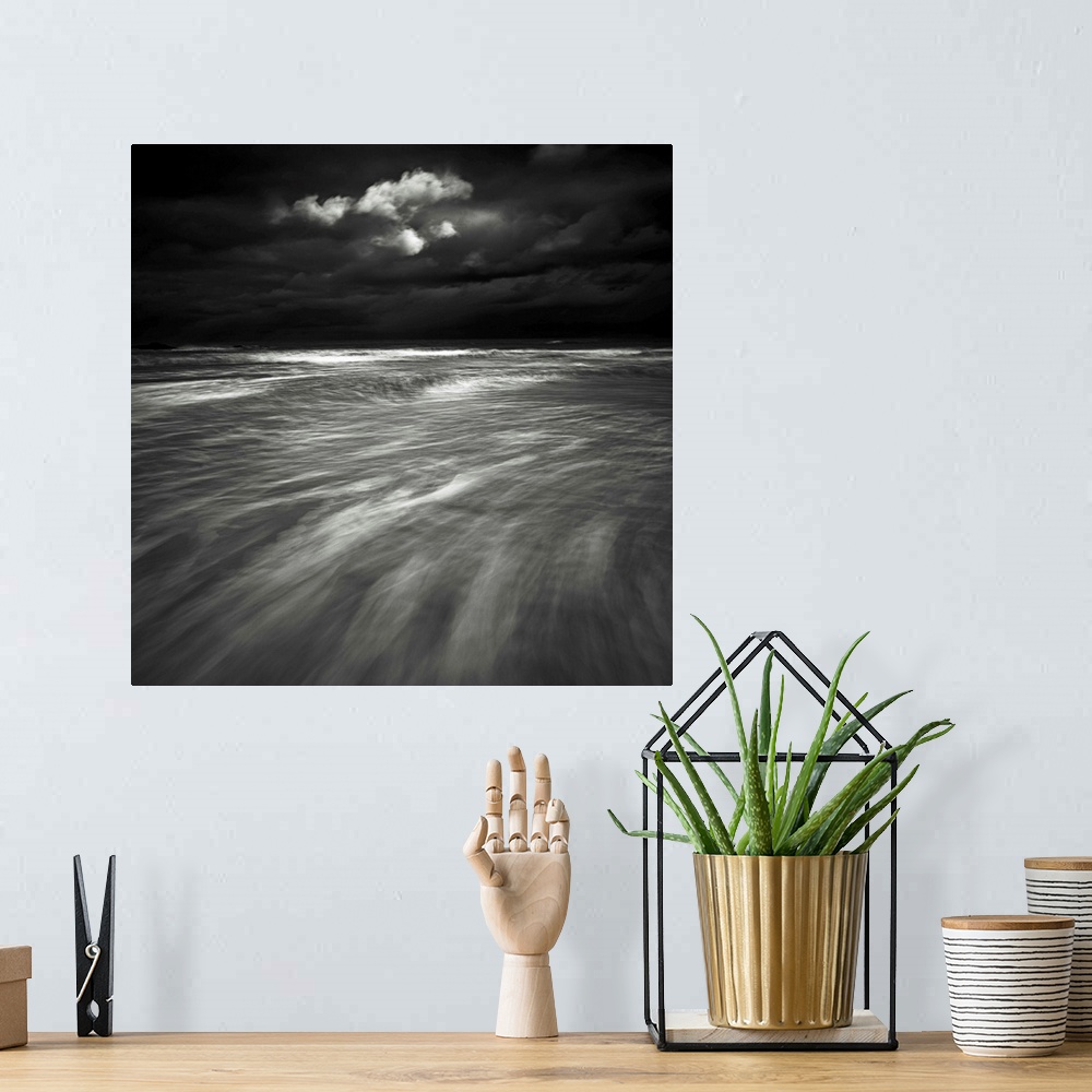 A bohemian room featuring A monochrome black and white sepia toned dramatic image of swooshing wavws and a lone cloud in a ...
