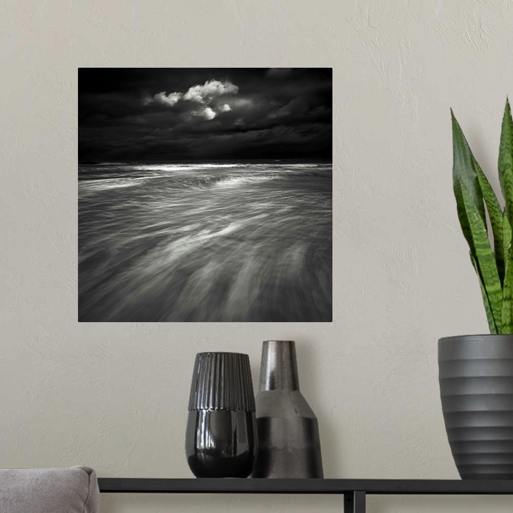 A modern room featuring A monochrome black and white sepia toned dramatic image of swooshing wavws and a lone cloud in a ...