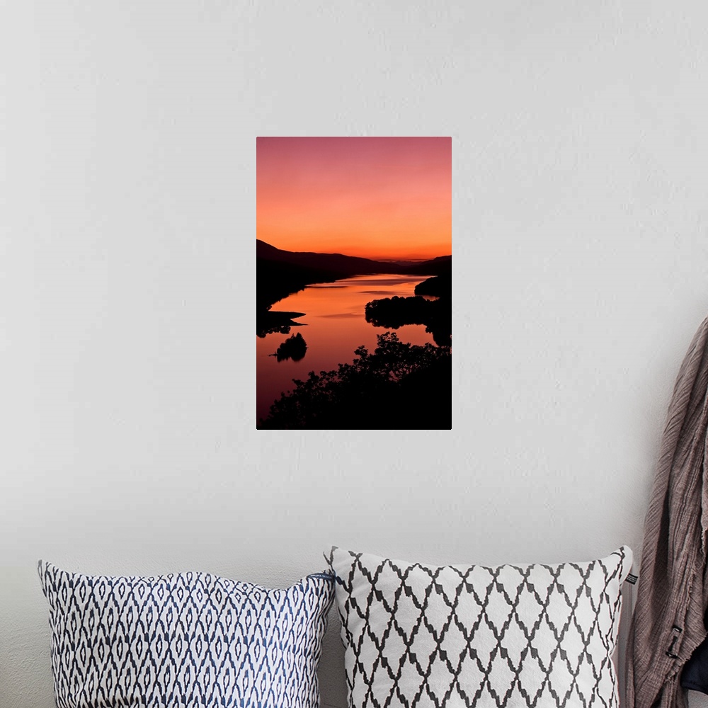 A bohemian room featuring An intense orange sunset landscape view over a loch in Scotland.