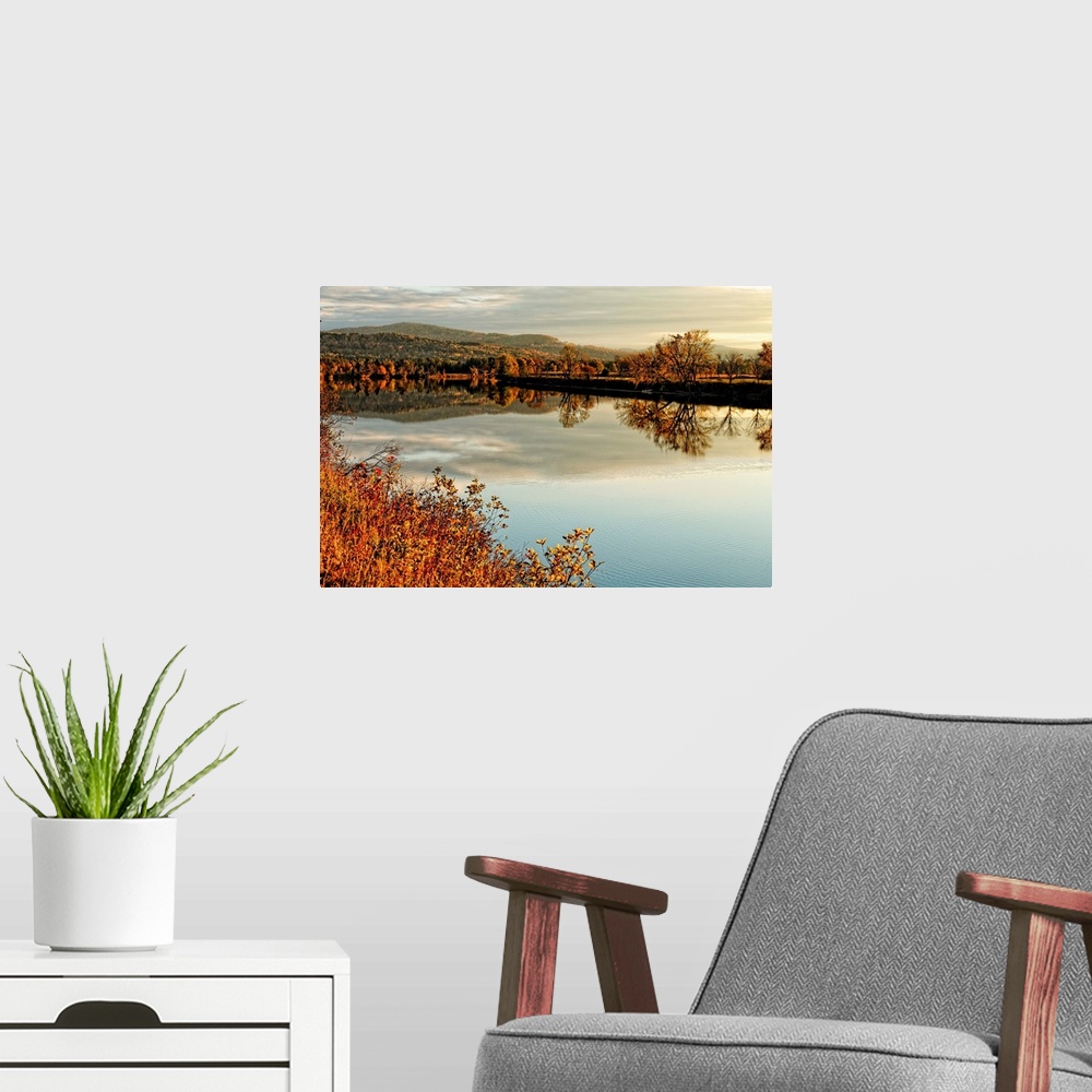 A modern room featuring Fine art photo of a calm lake at dusk with an autumn forest in the distance.