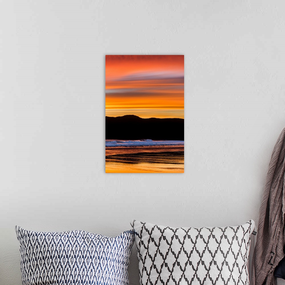 A bohemian room featuring Vibrant orange clouds reflected in the ocean water at sunset on the pacific coast.