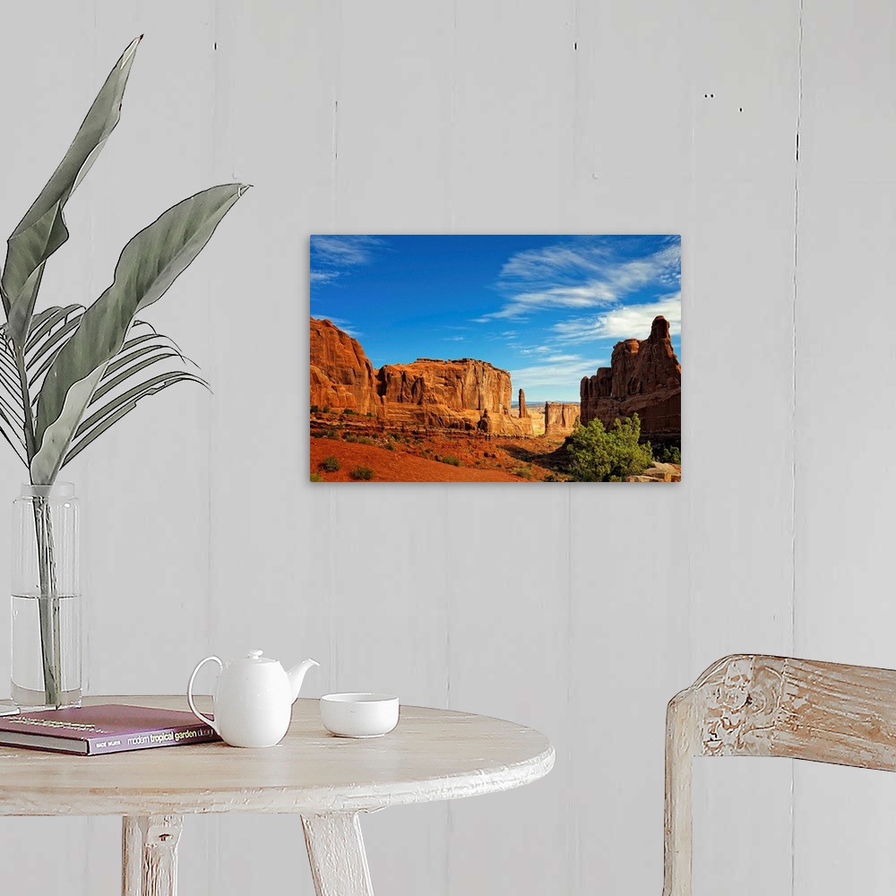A farmhouse room featuring Massive rock formations rise out of the desert floor with sheer cliff faces. Several shrubs grow ...