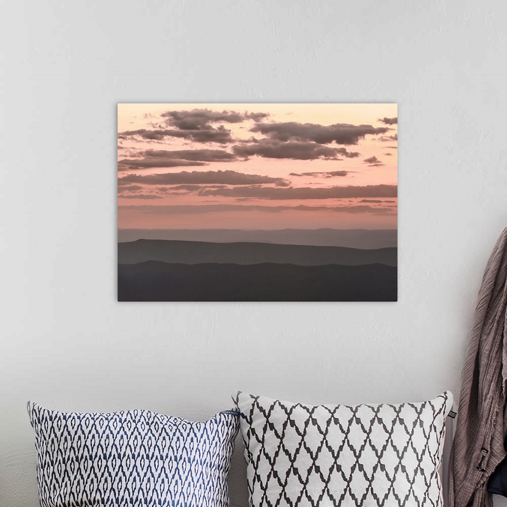 A bohemian room featuring Pale pink cloudy sky over dark hills at twilight.