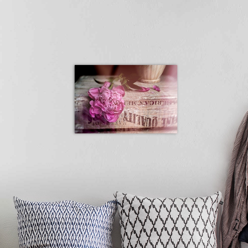 A bohemian room featuring Soft photograph of a pink peony resting on a weathered book.