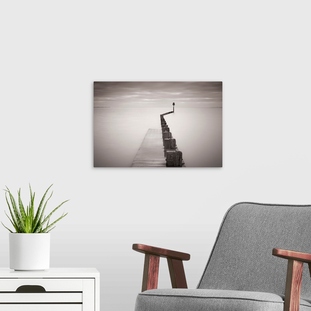 A modern room featuring Photograph of dock stretching into ocean under a cloudy sky.