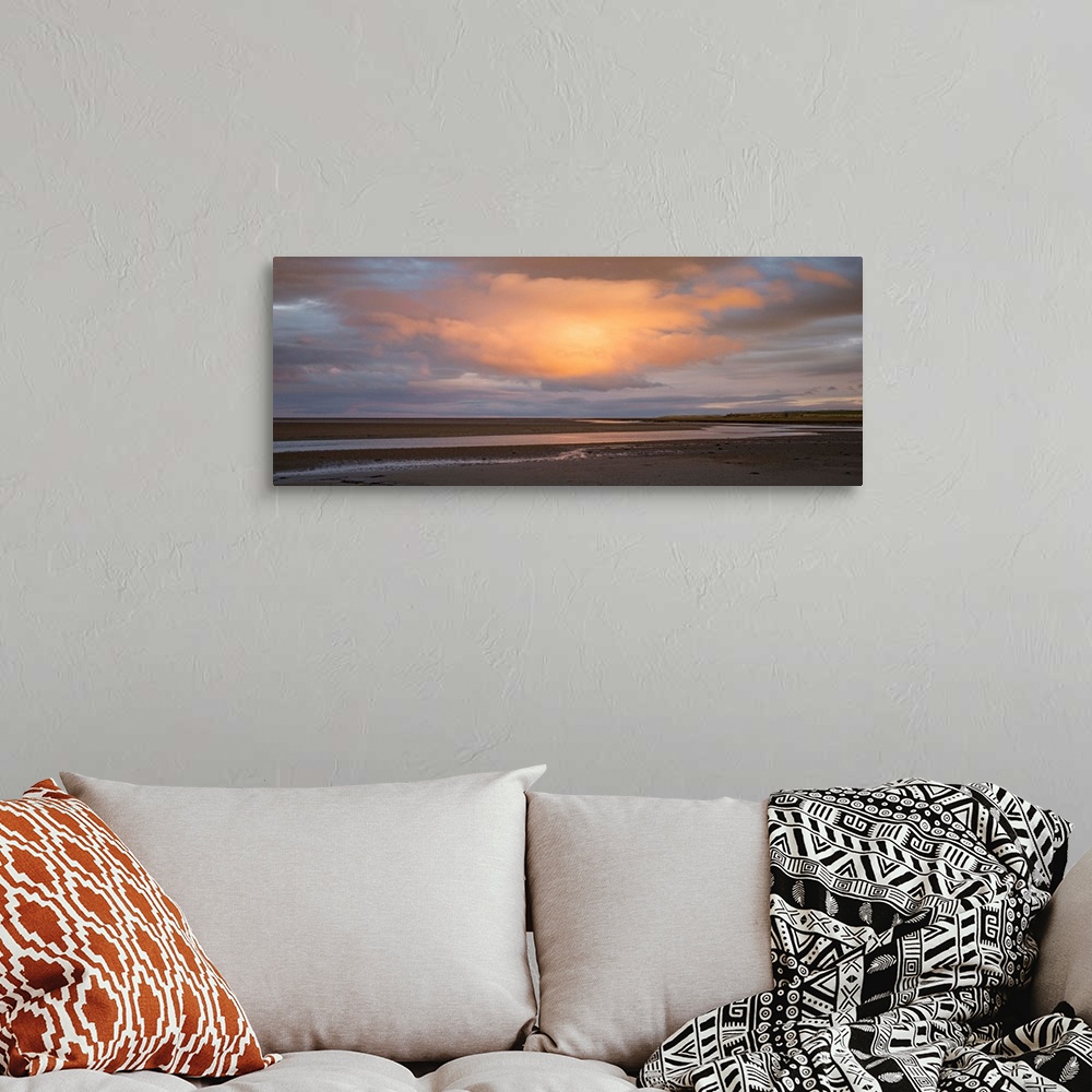 A bohemian room featuring Landscape photograph at sunset with a big orange cloud right in the center.