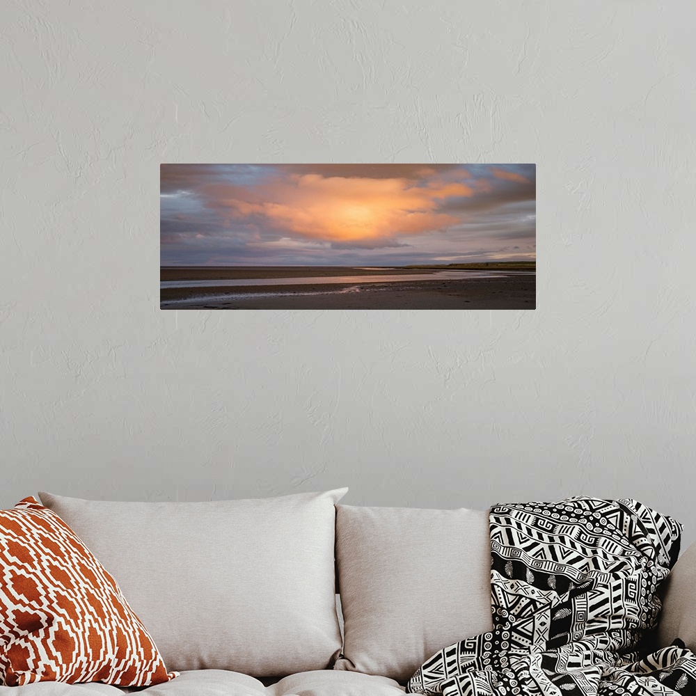 A bohemian room featuring Landscape photograph at sunset with a big orange cloud right in the center.