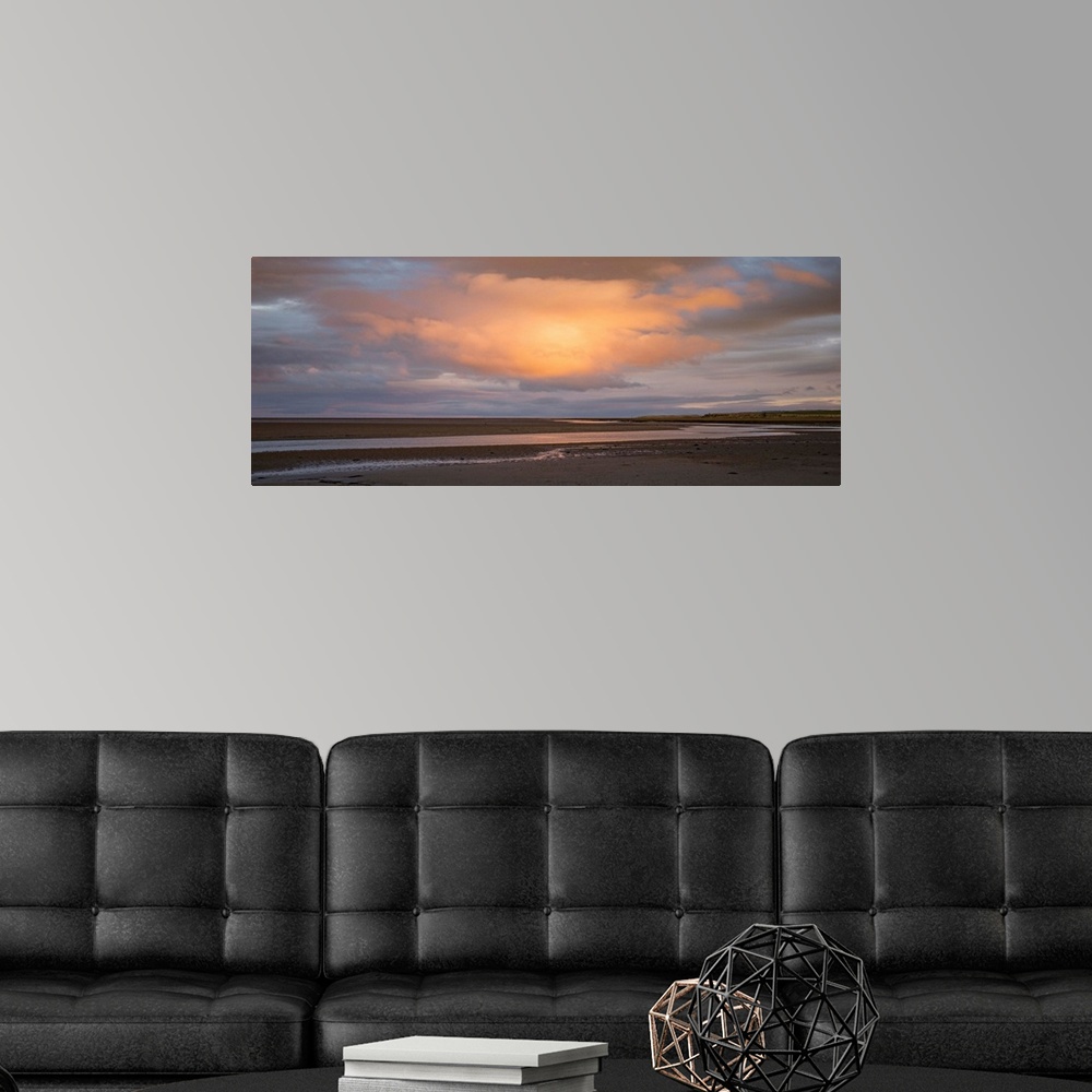 A modern room featuring Landscape photograph at sunset with a big orange cloud right in the center.