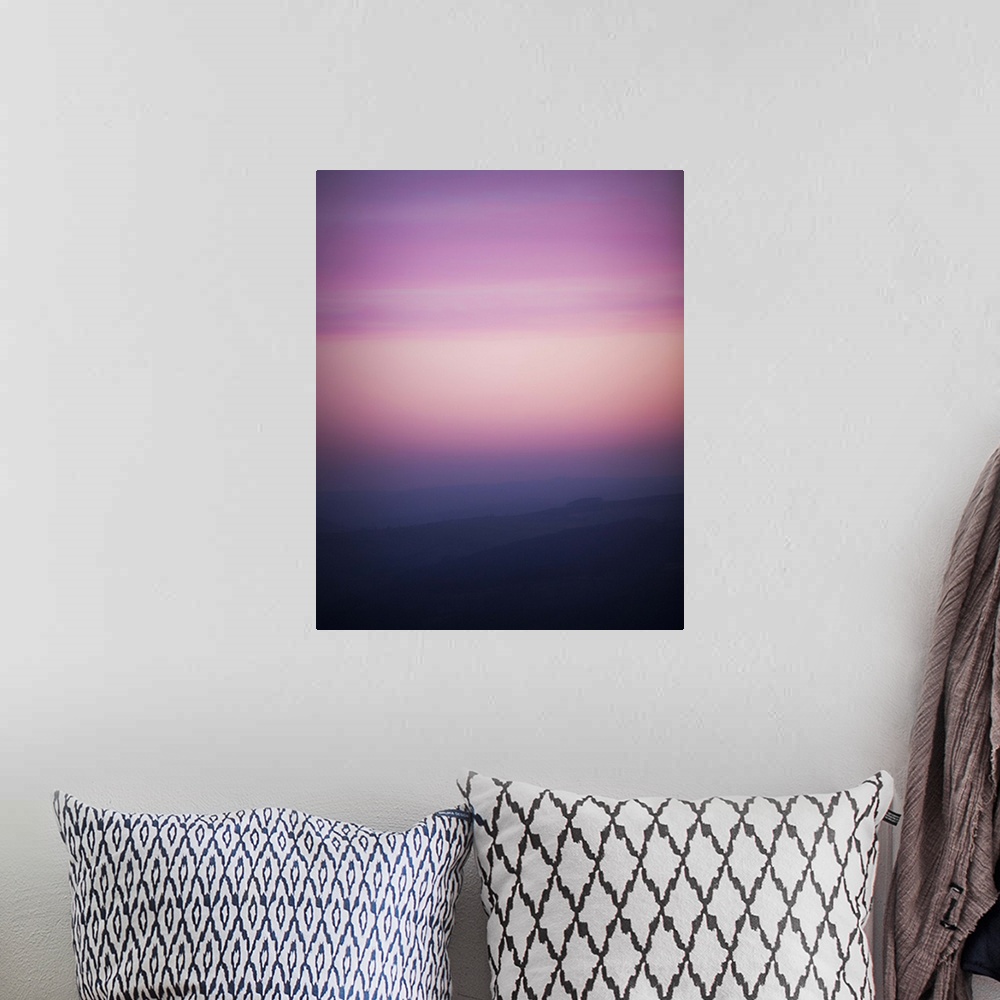 A bohemian room featuring A photograph of a silhouetted hazy landscape under a sunset sky.