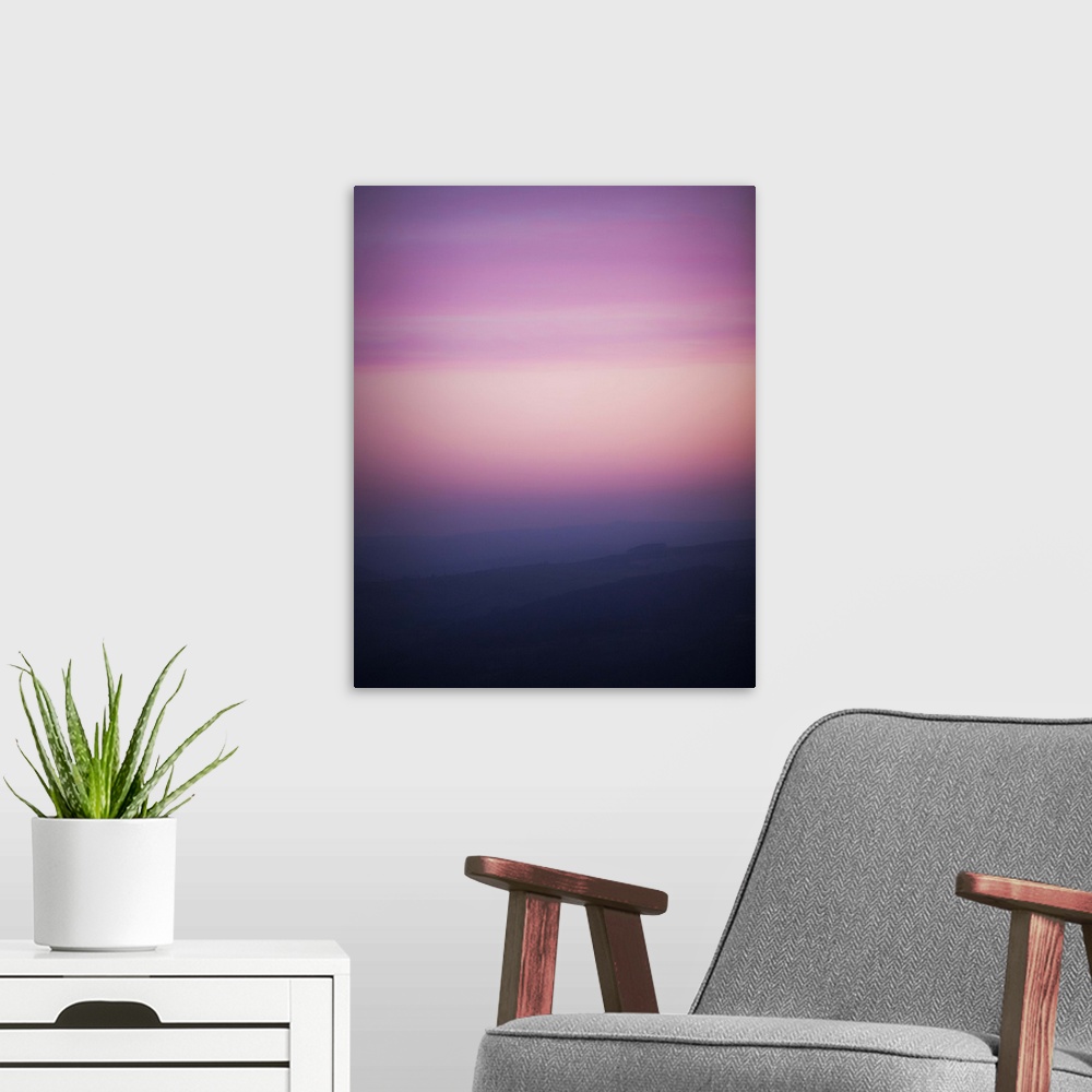 A modern room featuring A photograph of a silhouetted hazy landscape under a sunset sky.