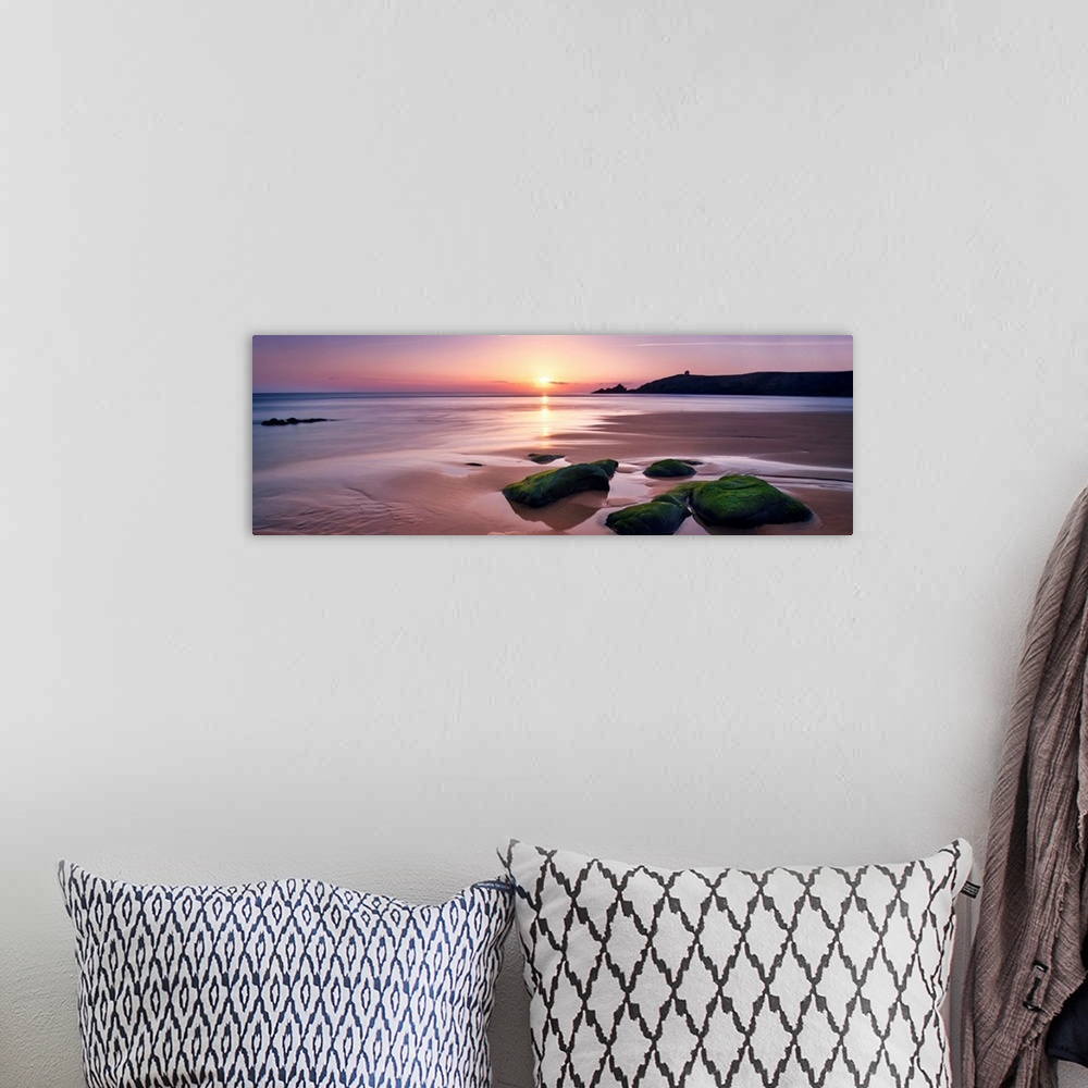 A bohemian room featuring Panoramic beach with rocks during a pink quite sunset in Brittany, France.
